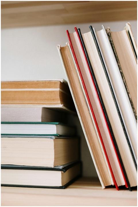 Close-up of assorted books stacked on a wooden boo