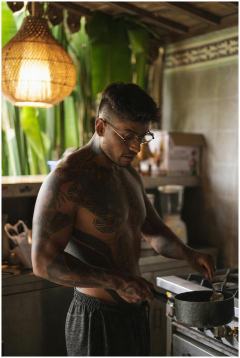 A shirtless man with tattoos cooking and stirring