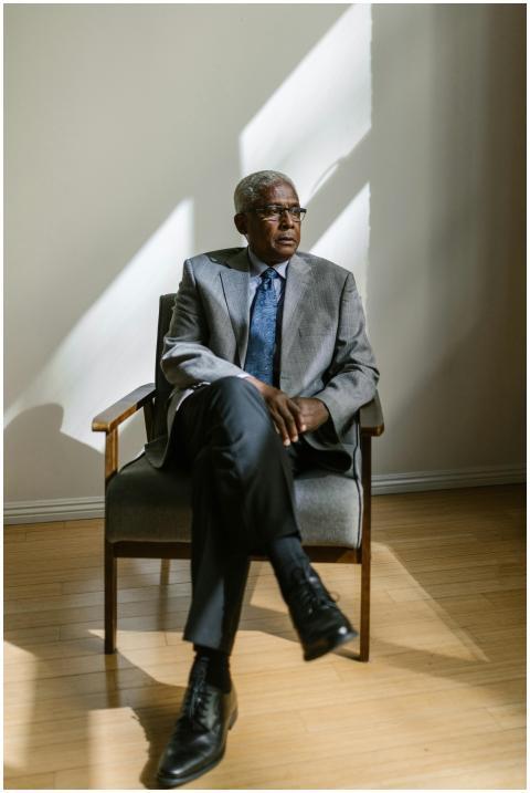 Senior man in a gray suit sitting in a wooden armc