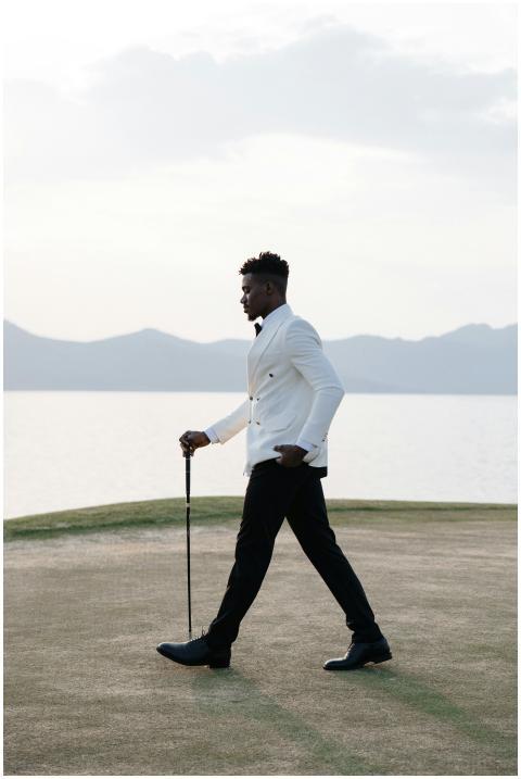 Stylish man in white jacket walking on golf course