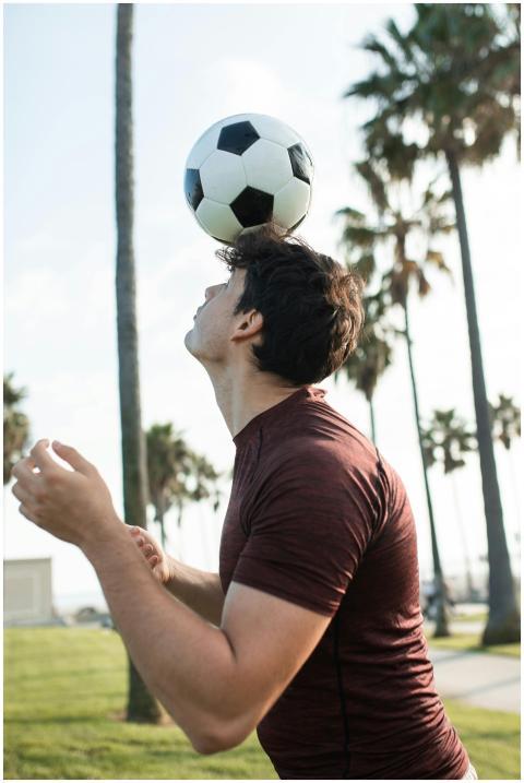 Young man practicing soccer skills by balancing a