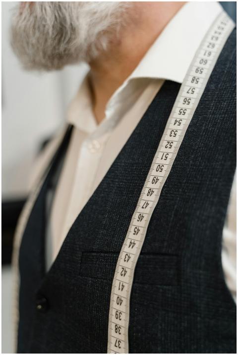 Close-up of a tailor in a suit with a measuring ta
