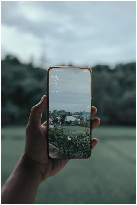 Smartphone with a rural scene displayed, held by a