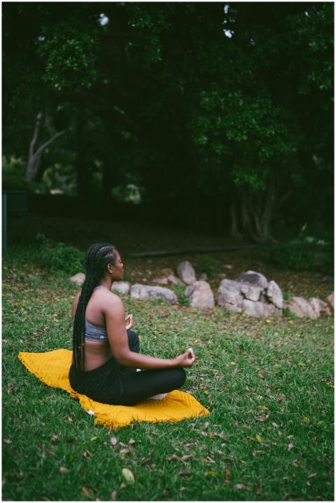 A woman meditating on a yellow mat in a serene out