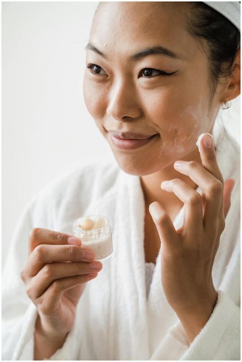Close-up of an Asian woman applying moisturizer du