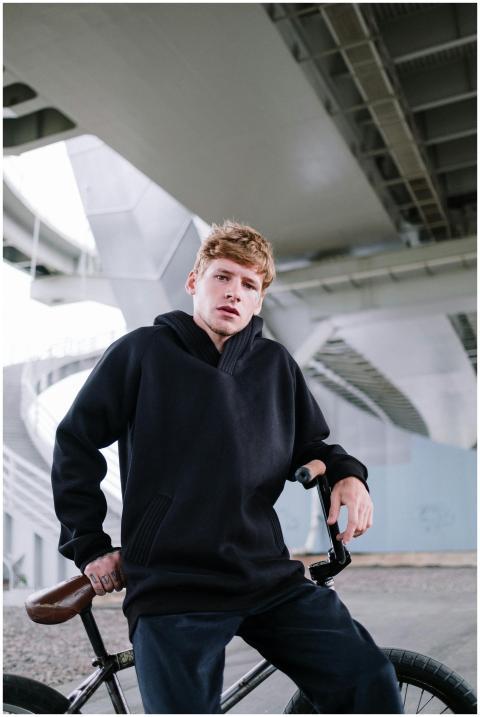 Caucasian man in black hoodie posing with BMX bike