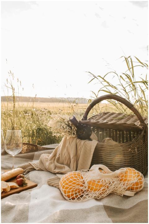 Tranquil picnic scene with wicker basket, wine, or