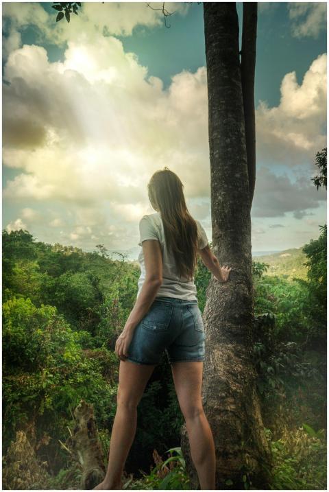 Woman stands by a tree, embracing nature during a