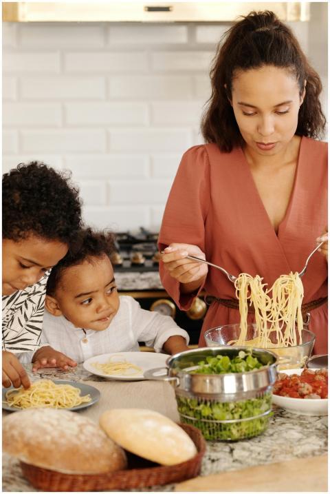 A mother prepares pasta with her children in a mod