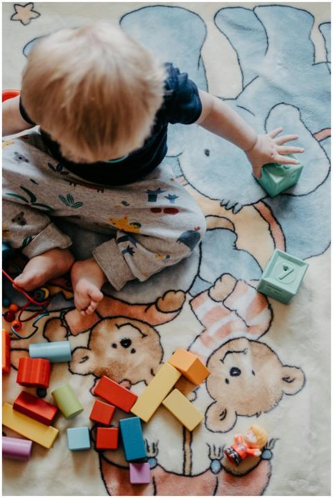 Adorable toddler playing with colorful blocks on c