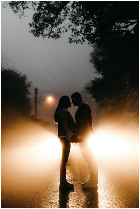 Silhouetted couple standing in front of car headli