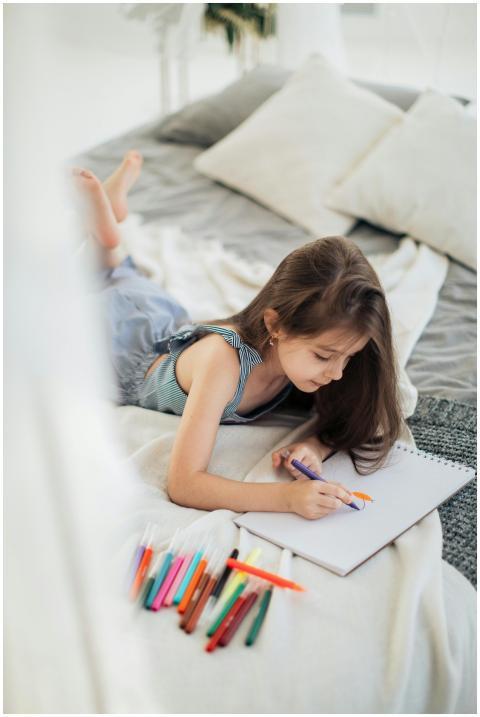 Young girl lying on bed, drawing with colored penc