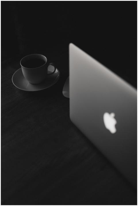 Black and white image showing a laptop and coffee