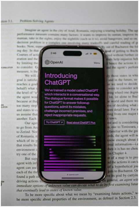 A mobile phone displaying ChatGPT is placed on top