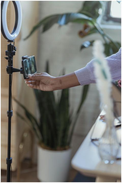 A woman adjusting a smartphone on a ring light sta