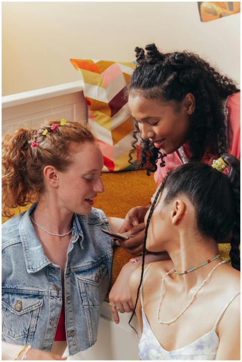 Three friends bonding over a smartphone indoors, e