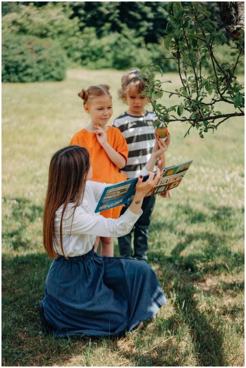 A teacher reads to children under a tree, promotin