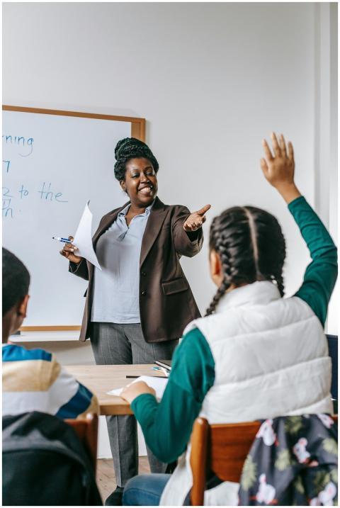 A teacher interacts with students in a classroom,