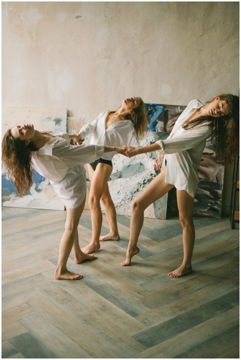 A trio of women elegantly dance in an artistic stu