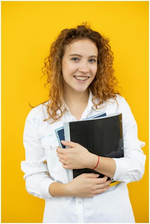 Happy young woman holding books with a bright smil