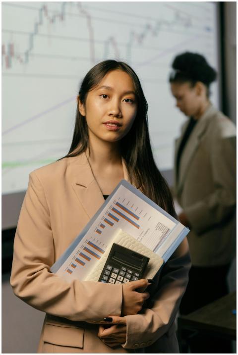 Confident Asian businesswoman holding charts and c