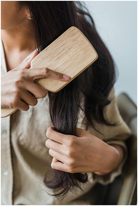 Close-up of a woman brushing her long dark hair wi