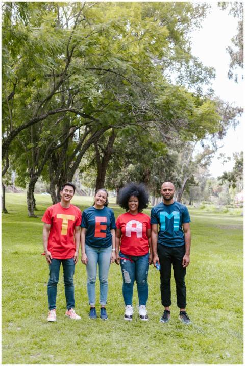 A diverse group of adults wearing TEAM shirts stan