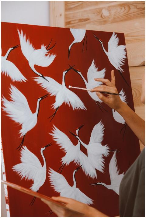 A painter adds details to a red canvas depicting e
