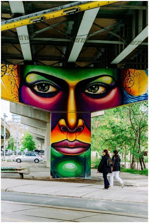 Colorful graffiti beneath an urban bridge with peo