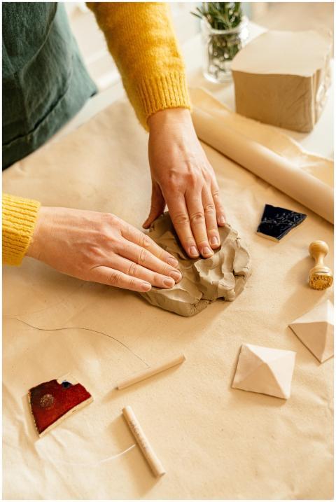 Close-up of hands molding clay on a work table wit