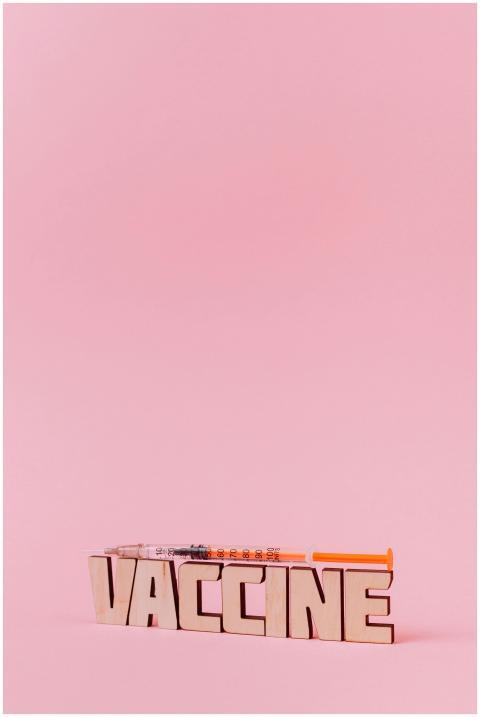 Wooden letters spelling 'VACCINE' and syringe on a