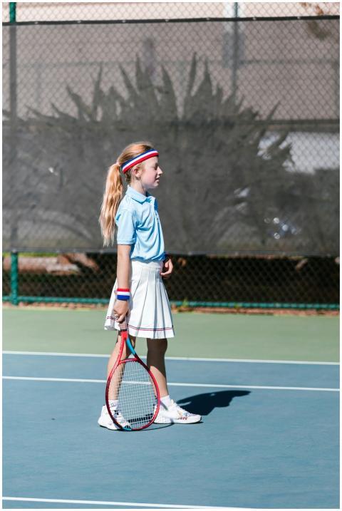 A young girl in sportswear playing tennis outdoors