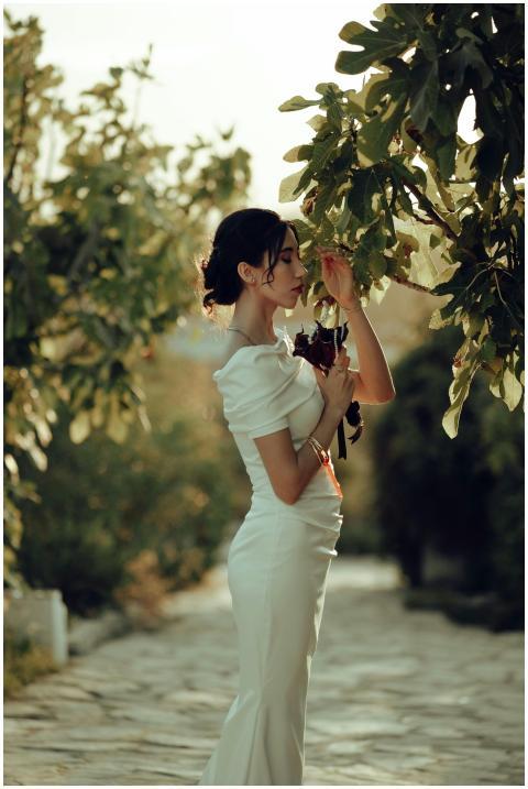 Elegant woman in a white dress stands in a sunlit