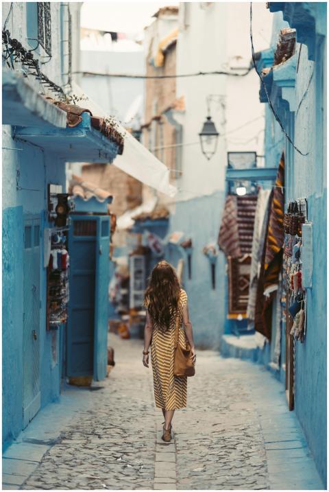A woman wanders through the vibrant blue alleyways