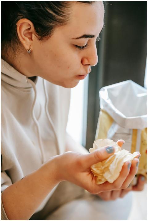 A young woman savors a handful of crispy potato ch