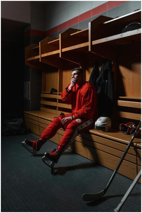 A hockey player in red uniform sits thoughtfully i