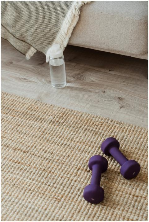 Home workout setup featuring dumbbells, water bott