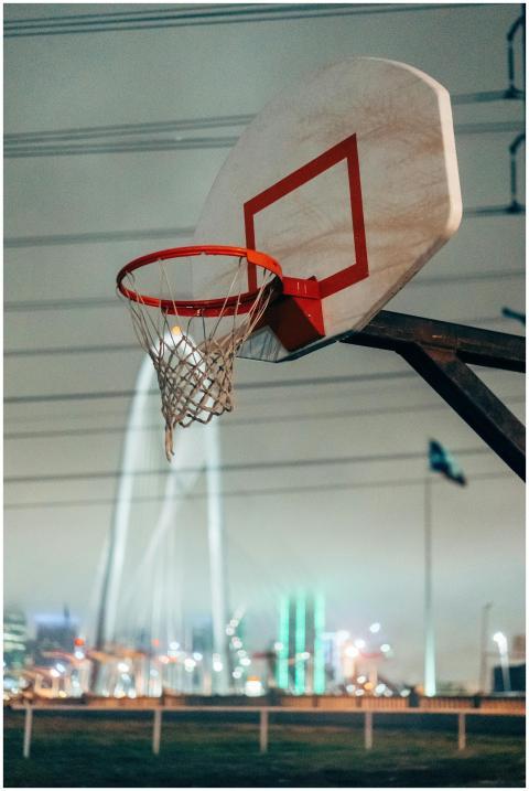 A basketball hoop set against the night skyline of