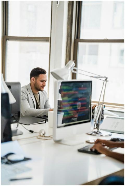 A young man working at a desktop computer in a bri