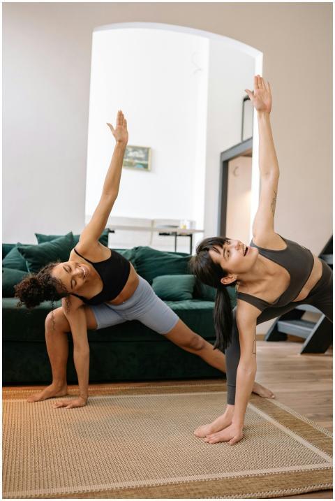 Two young women performing yoga poses together in