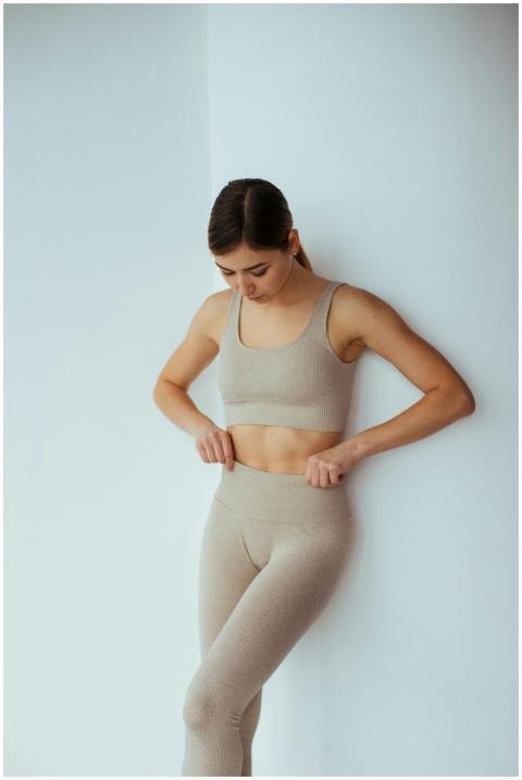 A woman in beige activewear adjusting her leggings