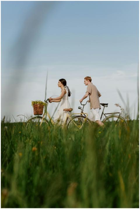 A couple biking side by side through a lush summer