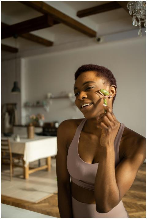 A woman in activewear using a jade roller for her