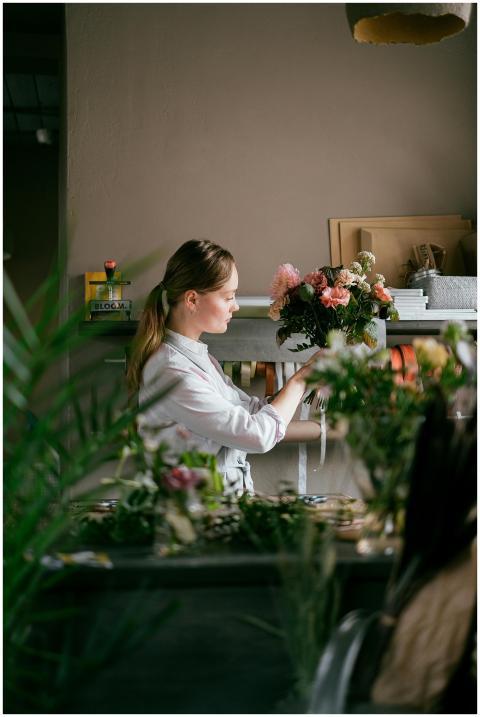Female florist arranging fresh flowers in a small
