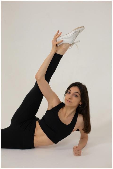 Flexible woman in activewear stretching leg, pract