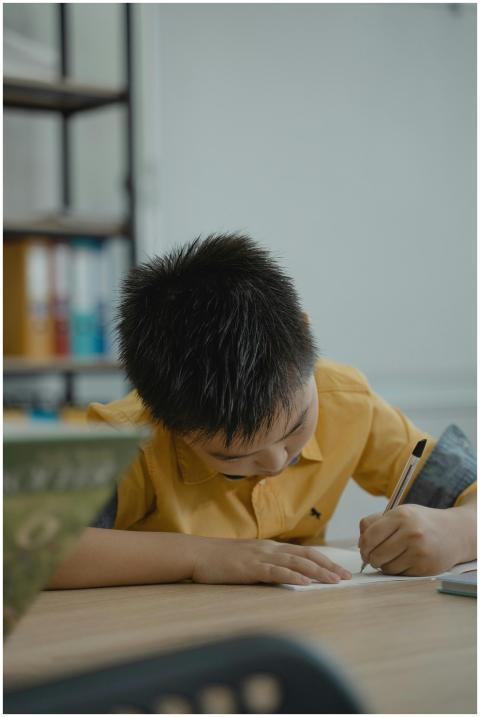 A young student in a classroom concentrating on wr