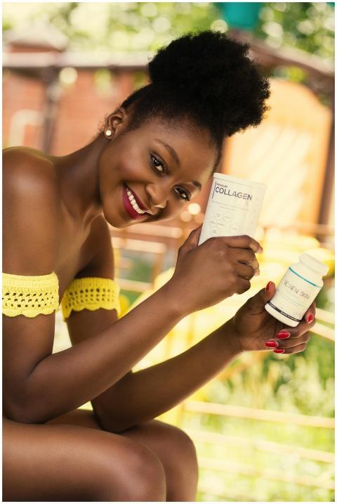 A joyful woman outdoors holding skincare products,