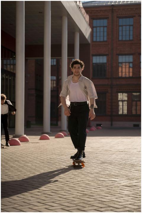 A young man skateboards through a sunlit urban are