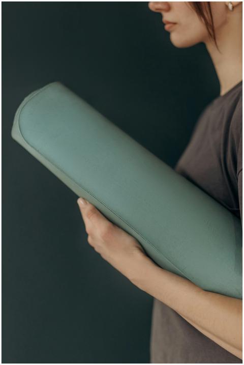 Close-up of a woman holding a yoga mat, suggesting