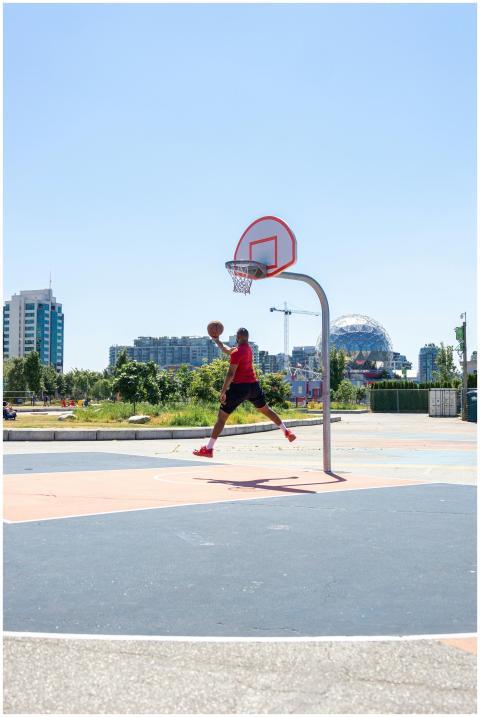 Athlete in red shirt jumps for a dunk on a sunny d